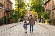 Mama prowadzi córkę z plecakiem szkolnym do szkoły ulicą polskiego miasteczka we wrześniowy poranek - polisa posagowa i oszczędzanie na start dziecka